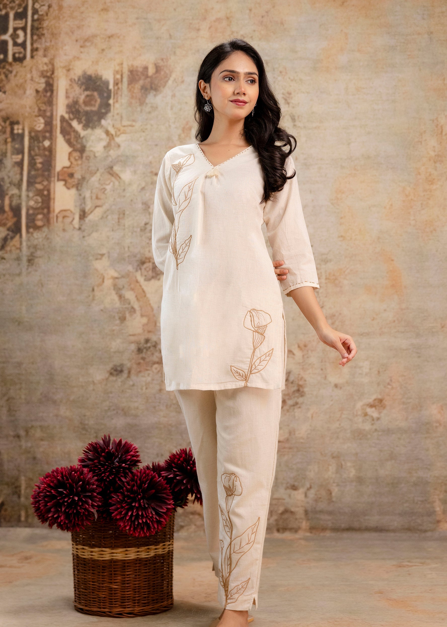 Woman wearing a cream-colored co-ord set with brown floral embroidery.
