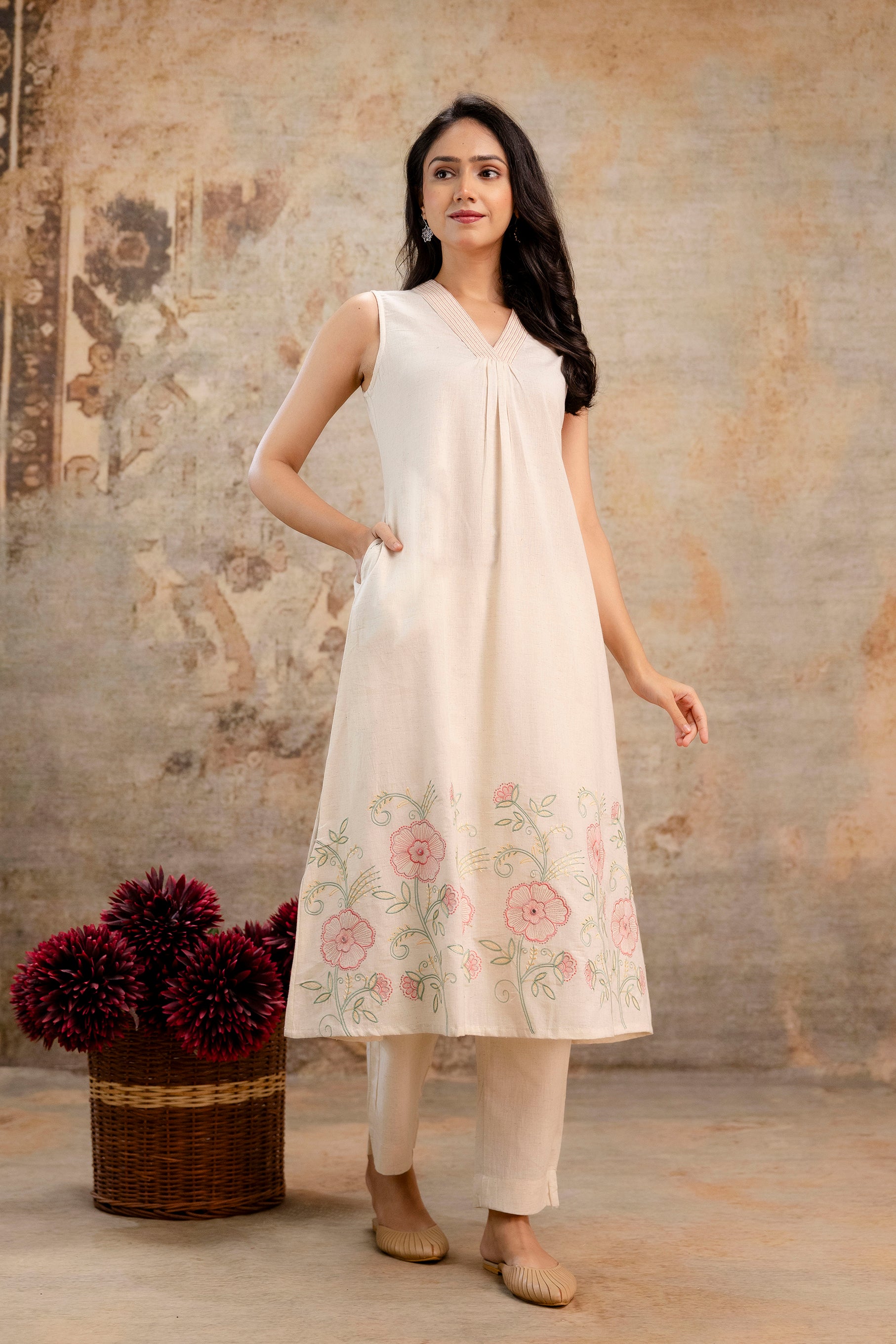 Sleeveless ivory Tanauri cotton kurti with soft pleats at the neckline.

Beautiful pastel floral embroidery along the hemline adds elegance.

Paired with simple off-white straight pants for a clean ethnic look.

Ideal for summer, casual wear, or daytime outings.

Keywords: cotton kurti set, Tanauri floral kurti, sleeveless ethnic wear, light Indian outfit.