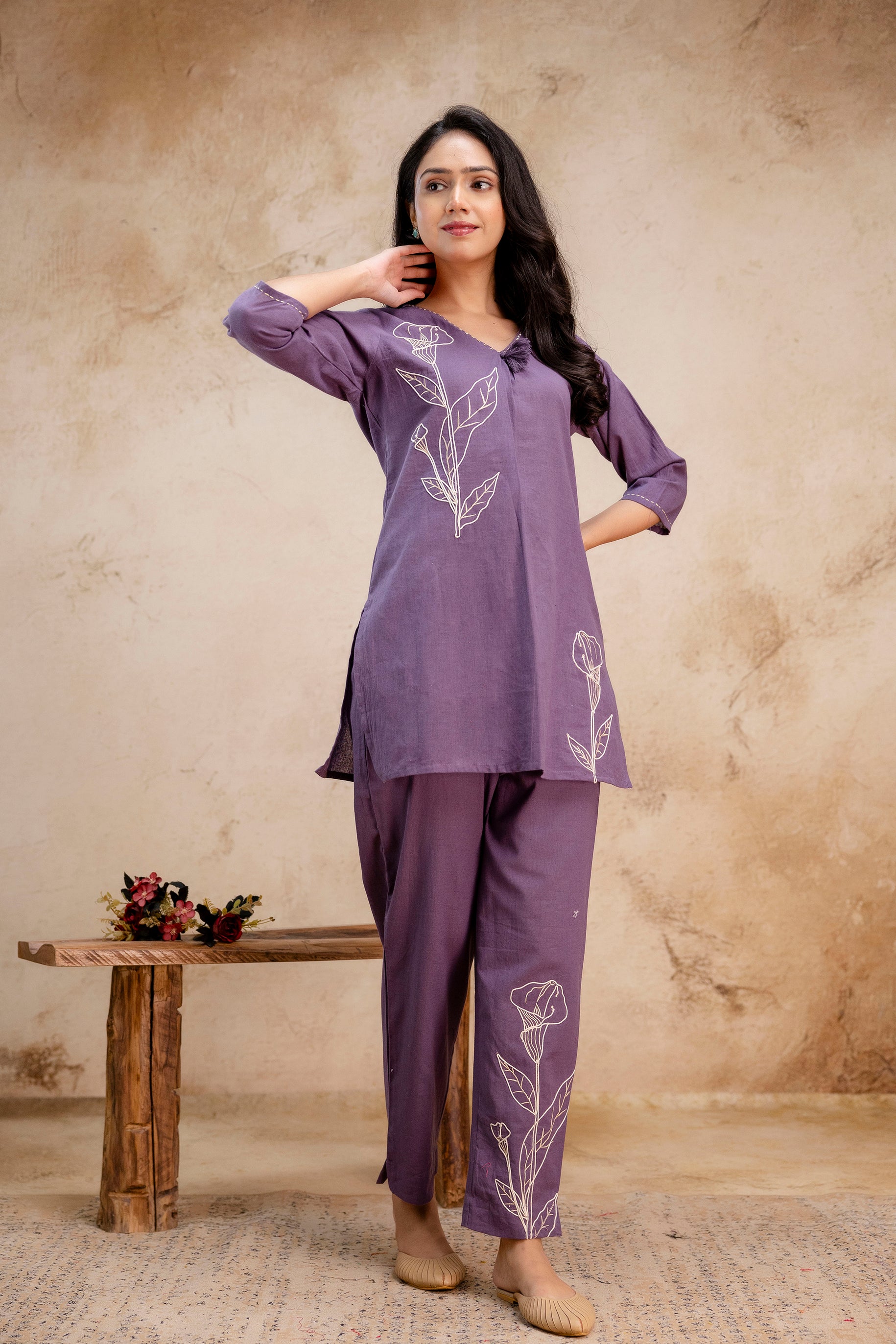 Stylish purple two-piece cotton co-ord set for women.

Kurti features white floral embroidery diagonally across the front.

Straight-fit pants with matching floral embroidery on one leg.

3/4 sleeves with a relaxed V-neckline for everyday wear.

Suitable for casual outings, office, or semi-ethnic occasions.

Keywords: purple co-ord kurti set, embroidered cotton wear, casual ethnic outfit, women’s stylish kurti.