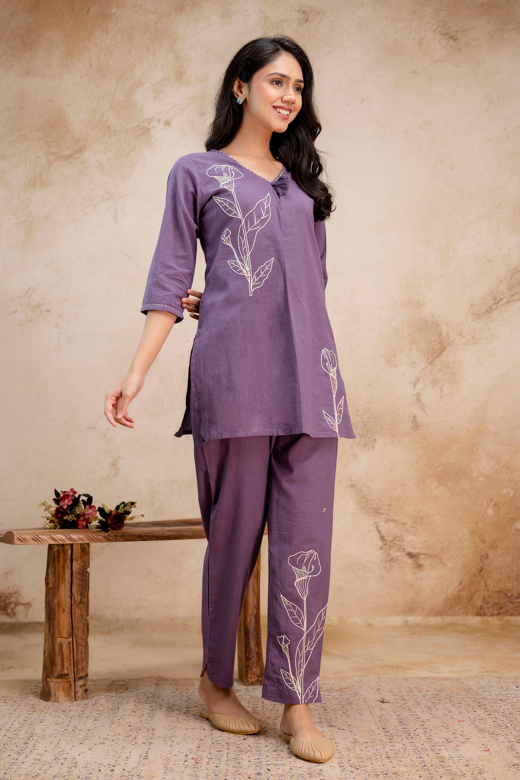 Elegant purple cotton co-ord set for women featuring floral embroidery.

V-neck kurti with white threadwork flower design from shoulder to hem.

Straight pants showcasing floral embroidery on the lower leg for a matching touch.

Three-quarter sleeves and relaxed fit suitable for daily or workwear styling.

Perfect blend of comfort and ethnic charm in a contemporary silhouette.

Keywords: women's cotton kurti set, embroidered purple co-ord, stylish everyday ethnic wear, kurta pant set with floral detailing.