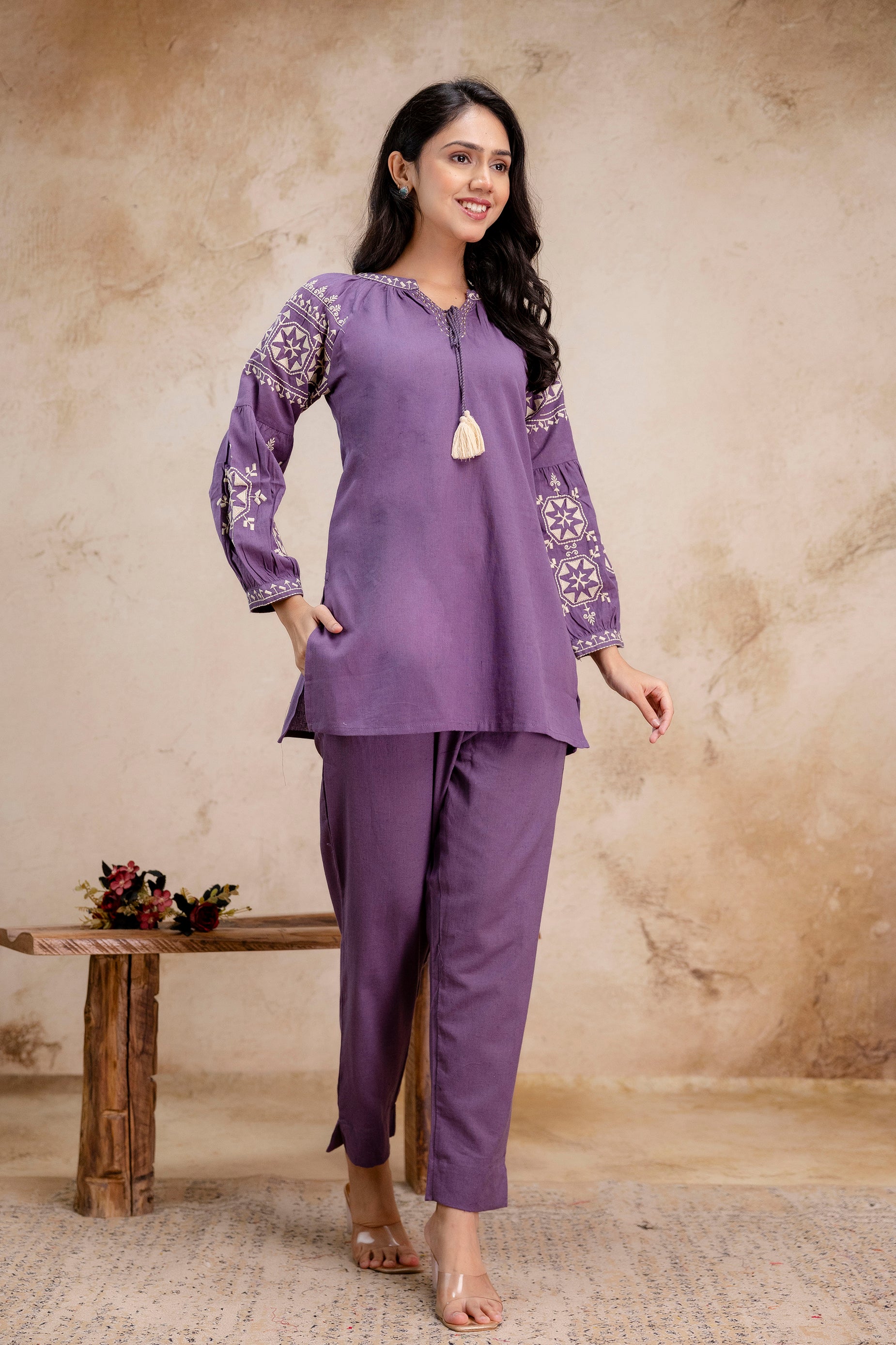 Tanauri lavender cotton kurti co-ord set with embroidered balloon sleeves – walking view  
Elegant lavender kurti and pant set in cotton fabric by Tanauri – floral sleeve detail  
Walking pose of Tanauri lavender ethnic kurti set with tassel tie and full sleeves  
Lavender embroidered cotton kurti with tapered pants – Tanauri ethnic outfit  
Model wearing Tanauri lavender cotton kurti with balloon sleeves – front movement shot  
Tanauri women’s kurti set in lavender with cotton trousers 