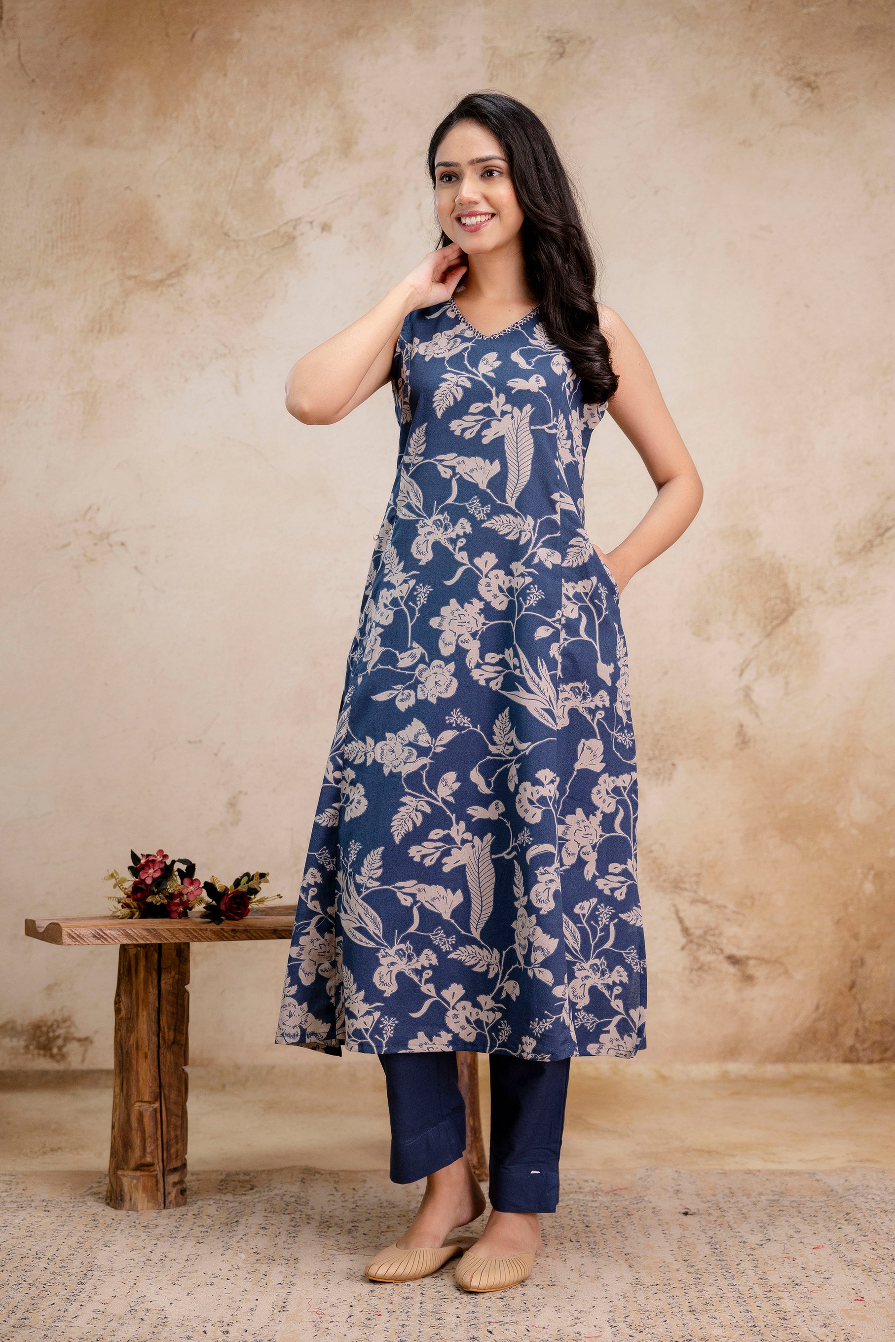 1. Side pose of sleeveless indigo kurti with beige floral block print  
2. Indigo cotton A-line kurti with ethnic floral print and navy pants  
3. Women’s indigo sleeveless kurti set with pockets and floral design  
4. Elegant printed indigo kurti with beige motifs – side-facing front view  
5. Model wearing sleeveless indigo floral kurti with straight trousers  
6. Indigo blue ethnic kurti outfit for women – summer casual wear  
7. Floral printed A-line kurti in indigo with beige straight-fit pants