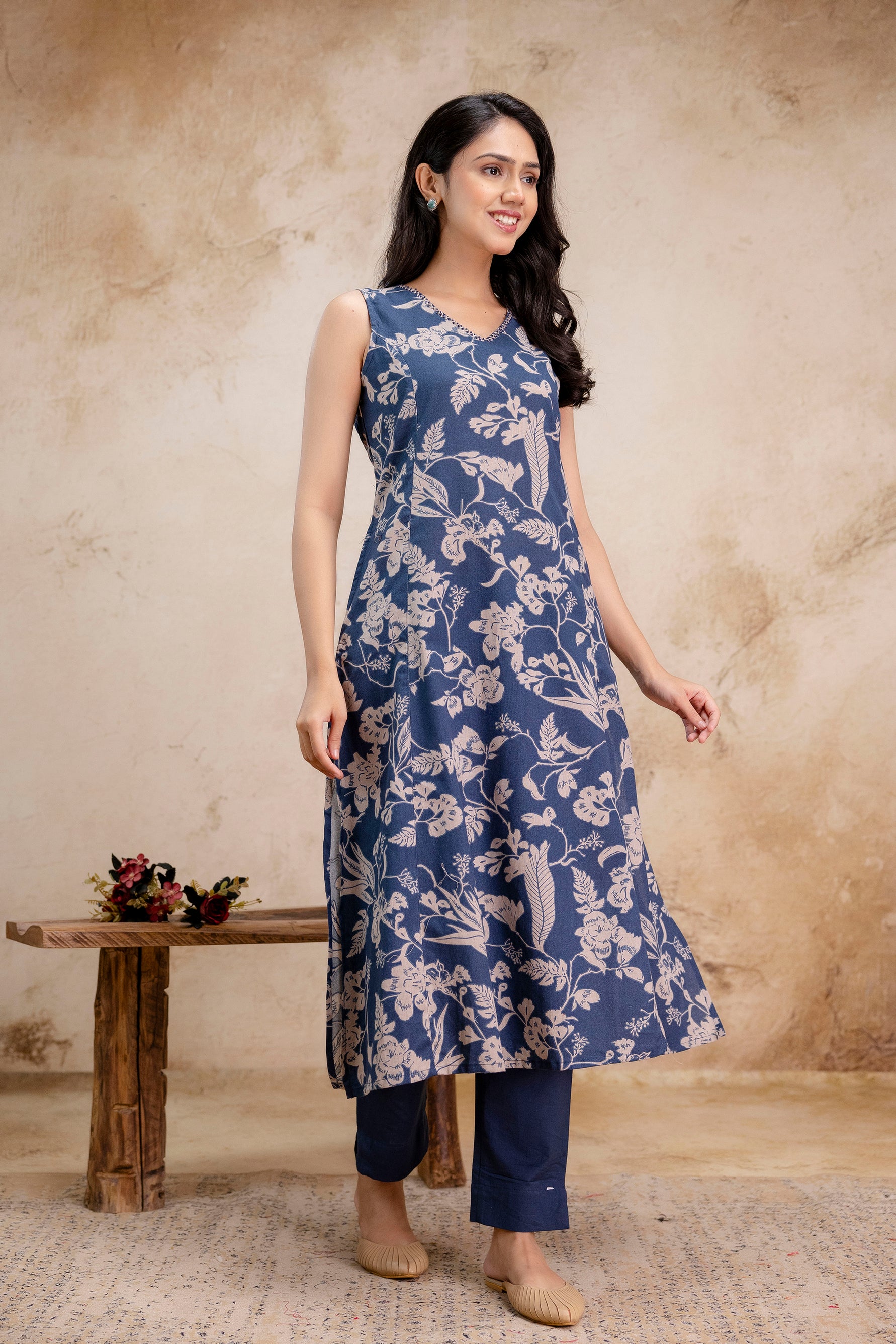 1. Sleeveless indigo kurti with beige floral print and navy straight pants  
2. Side-front pose of indigo cotton A-line kurti set with ethnic floral design  
3. Women’s indigo printed kurti outfit with flared silhouette and pockets  
4. Sleeveless ethnic kurti set in indigo blue with beige floral block print  
5. Elegant indigo summer kurti for women with straight-leg trousers  
6. Model wearing indigo A-line kurti with ethnic floral print – side angle  
7. Lightweight cotton sleeveless kurti in indigo with