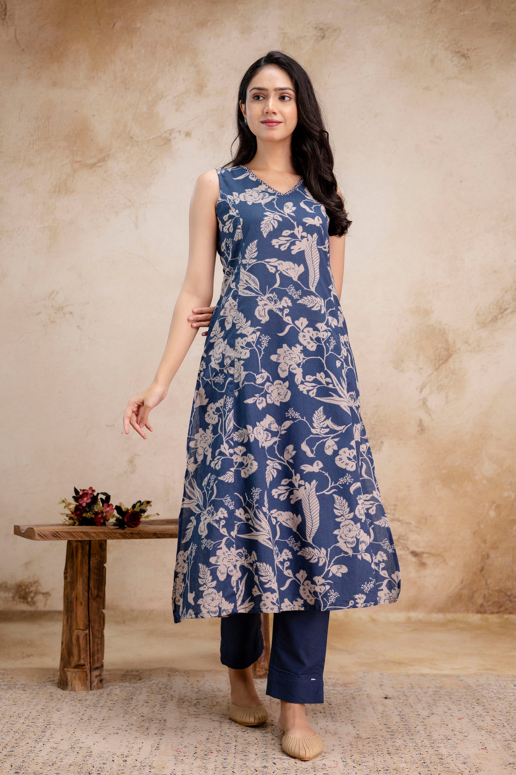 1. Front view of indigo sleeveless cotton kurti with beige floral print  
2. Indigo A-line kurti with traditional block print paired with navy pants  
3. Women’s ethnic sleeveless kurti set in indigo blue – floral printed look  
4. Elegant cotton kurti set with sleeveless flare cut and straight trousers  
5. Model wearing indigo blue floral ethnic kurti with pants – front pose  
6. Floral printed indigo kurti in breathable cotton fabric – full view  
7. Summer ethnic wear for women – indigo kurti with beige