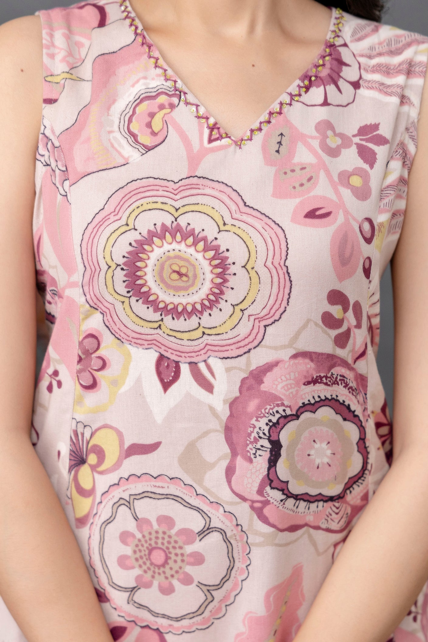 Close-up view of a sleeveless cotton kurti with soft V-neckline

Intricately embroidered neckline in contrast pink and mustard thread

Fabric base in pastel blush pink featuring bold mandala and floral prints in mauve, plum, yellow, and ivory

Lightweight, breathable texture ideal for warm weather

Artistic and contemporary ethnic print design for casual chic wear

