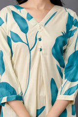 Close-up view of a cream kurti with bold teal blue botanical prints featuring abstract leaves and fruit shapes.

V-neckline accentuated with four fabric-covered buttons in matching cream and teal shades.

The pleated front adds gentle structure and flow to the garment.

3/4th sleeves are slightly puffed with a tailored hemline, echoing the teal print for cohesion.

The cotton fabric has a natural matte texture, contributing to an airy, breathable look.

The image focuses on the upper torso, showing elegant 