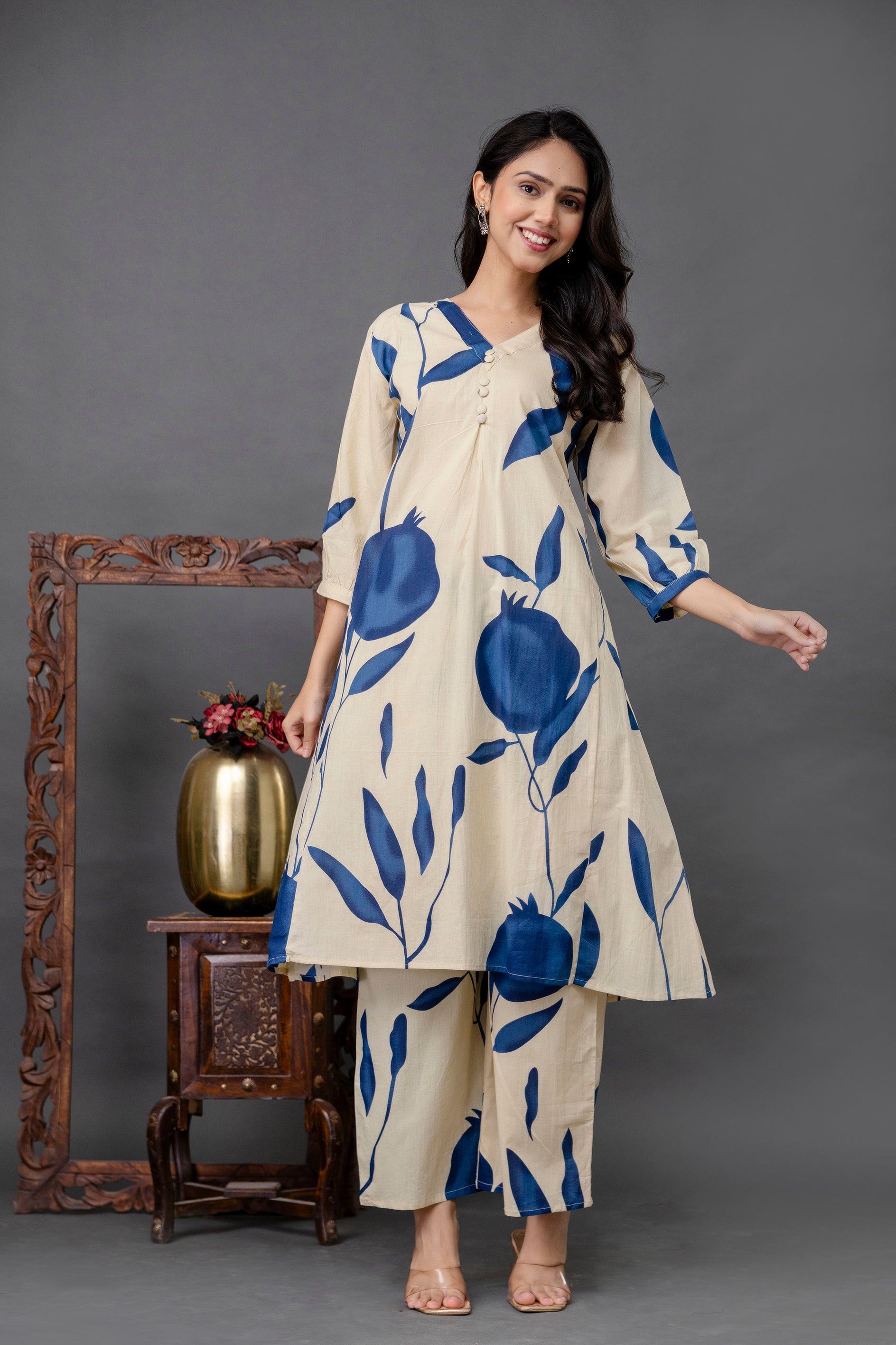 Beige cotton kurta set with bold blue pomegranate and leaf print

Features asymmetrical yoke with fabric buttons and pleats under bust

Three-quarter sleeves with all-over matching print

Paired with coordinated printed straight-fit pants

Lightweight, breathable fabric perfect for everyday summer wear

Model styled simply to highlight the bold, botanical print design