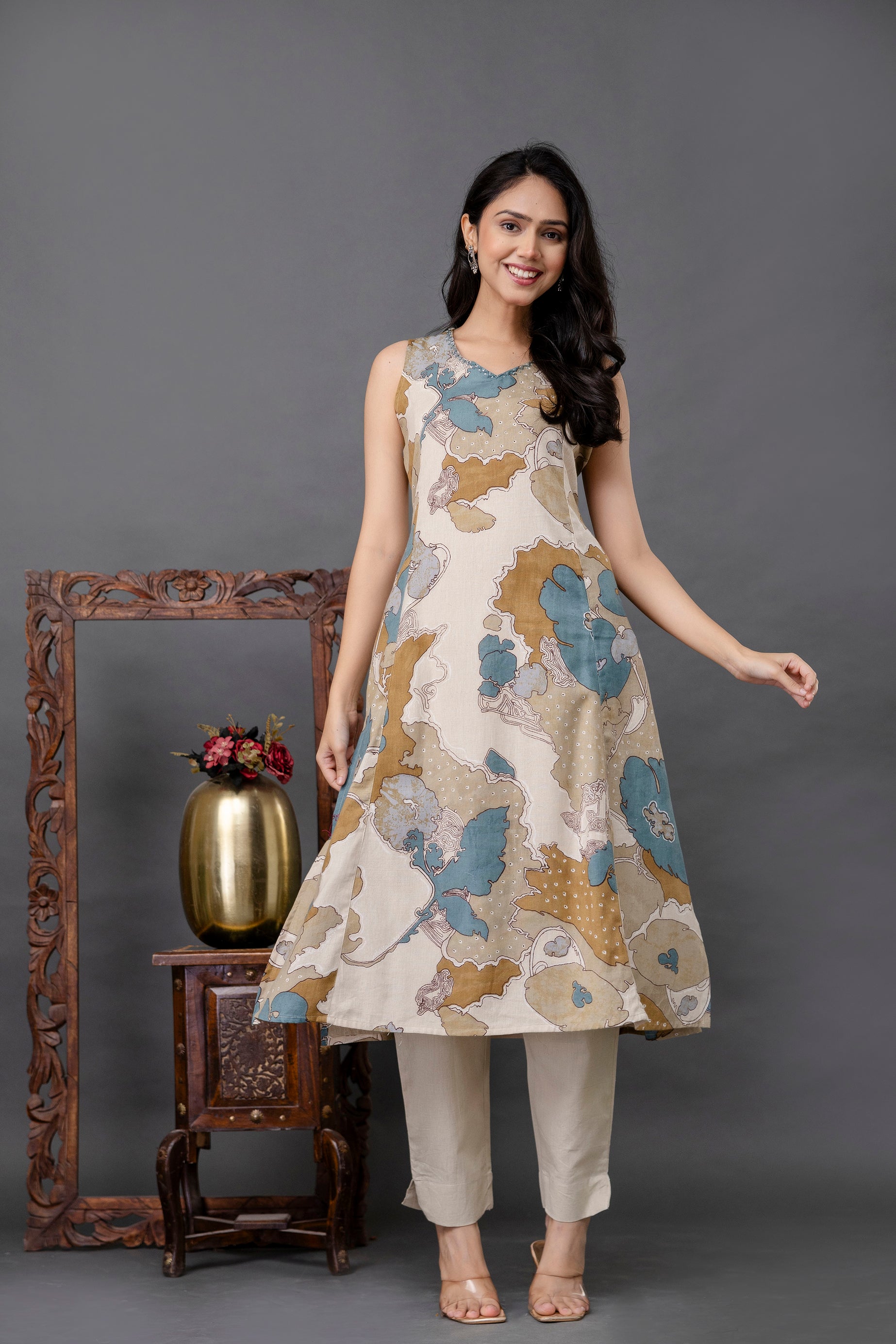 Sleeveless A-line kurti with abstract floral print in earthy tones

Beige cotton base adorned with shades of blue, olive, and mustard

Features round neckline and flared hem for breezy comfort

Light ethnic wear ideal for summer or casual outings

Paired with straight beige cotton pants for a complete Indo-western look