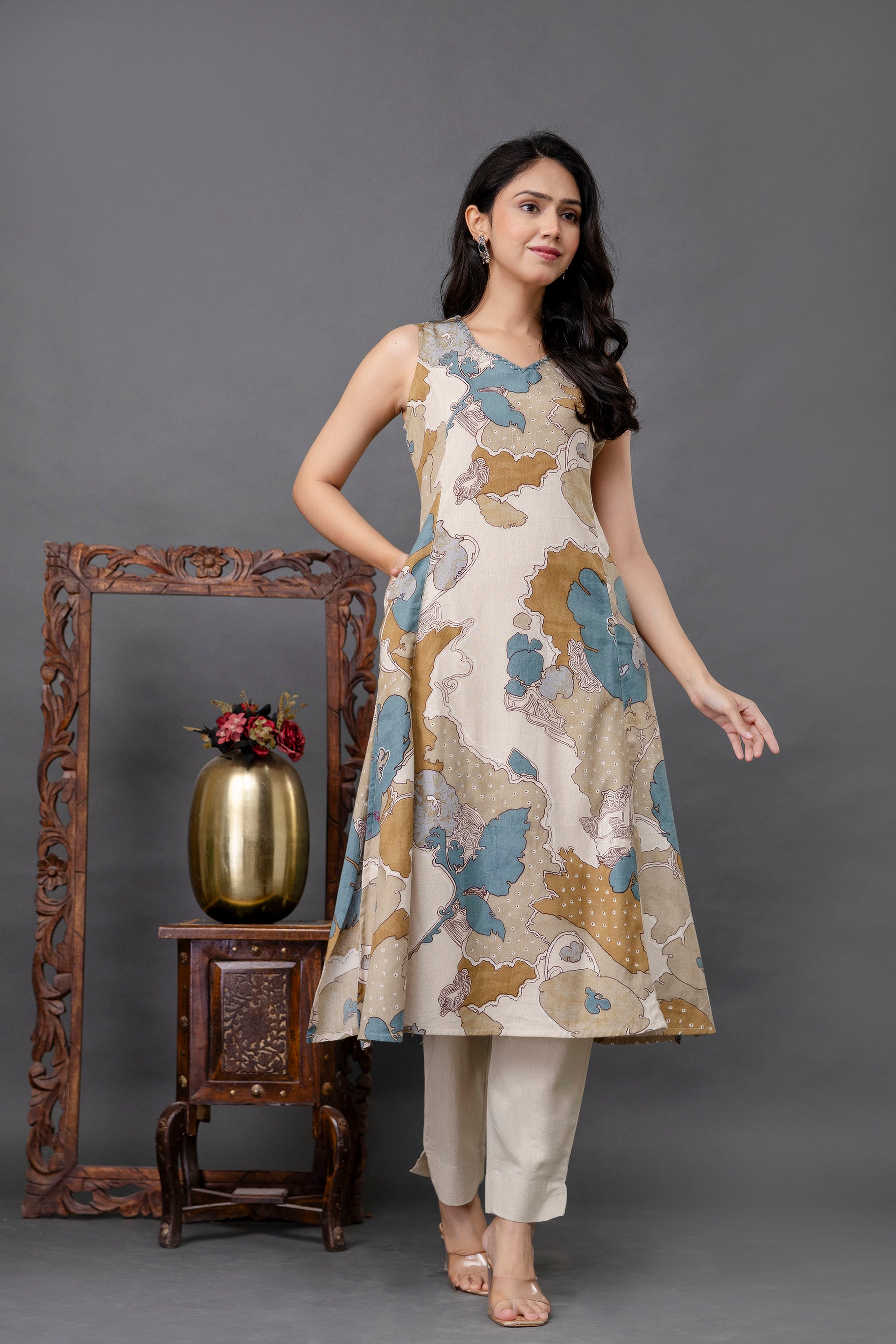 Sleeveless printed cotton kurti featuring an A-line silhouette

Abstract floral design in mustard, teal, and beige tones on off-white base

Round neckline and structured flare give a flattering fit

Includes functional side pockets for added utility

Styled with beige ankle-length straight pants for a minimal ethnic look