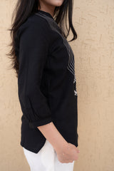 Person wearing a black top with white patterns against a beige background