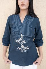 Navy blue top with white floral design worn by a person against a beige background