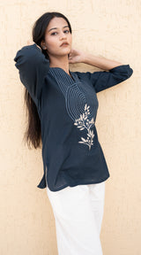 Woman wearing a dark blue top with floral design against a beige background