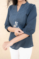 Blue top with white embroidery on a beige background