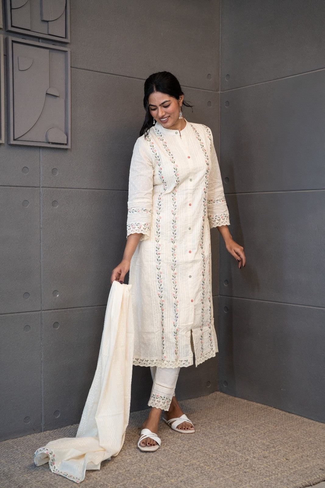 A woman modeling 'Moon Dew Dupatta Set' by Tanauri, featuring a white cotton kurti and trousers with delicate multicolored embroidery, holding a textured, white dupatta