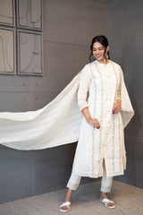 A woman modeling 'Moon Dew Dupatta Set' by Tanauri, featuring a white cotton kurti and trousers with delicate multicolored embroidery, holding a textured, white dupatta