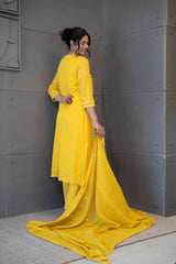 A woman modeling 'Marigold Magic Dupatta Set' by Tanauri, featuring an yellow cotton kurti and trousers with delicate floral embroidery, holding a textured, yellow dupatta.