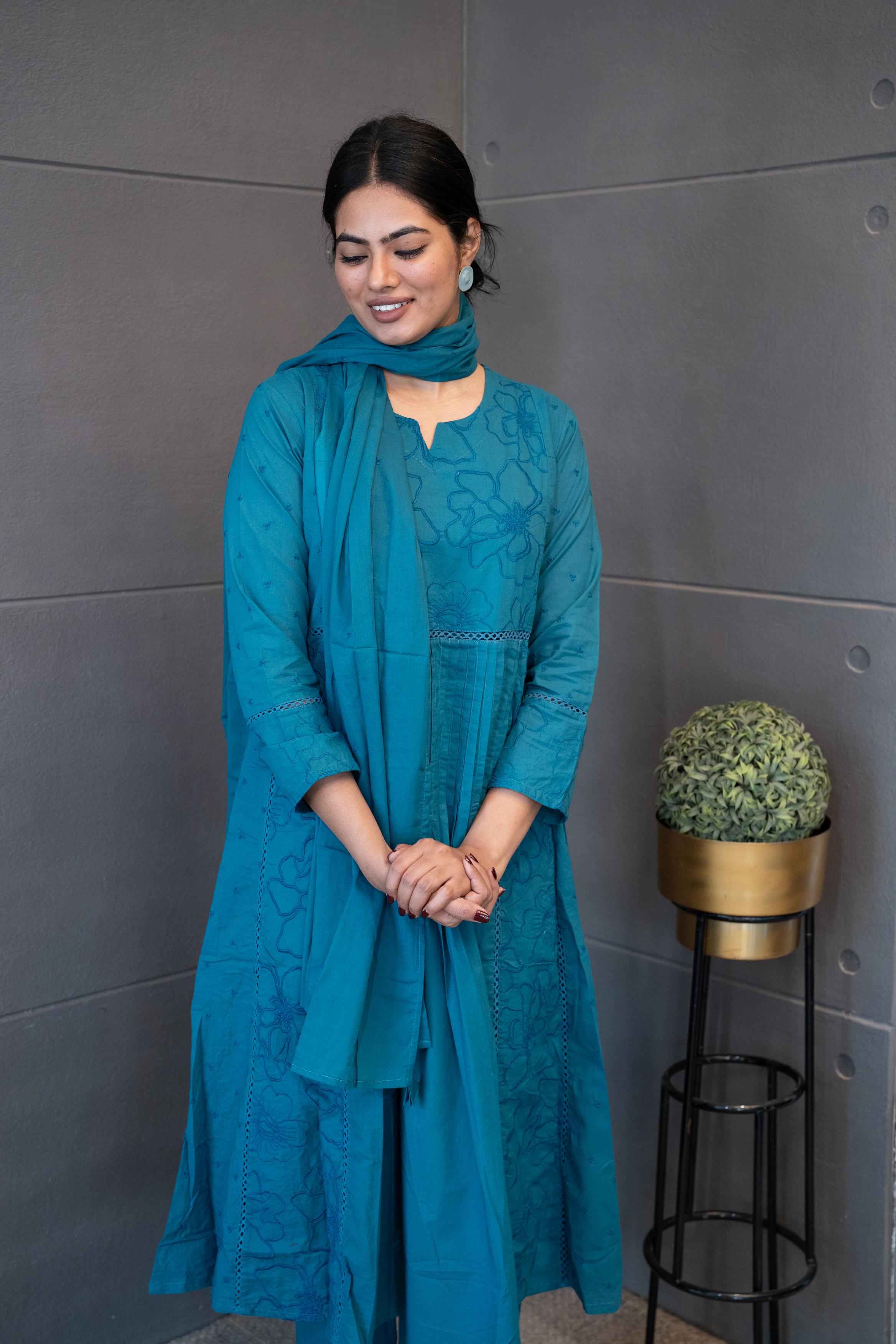 A woman modeling 'Blue Oasis Dupatta Set' by Tanauri, featuring a blue cotton kurti and trousers with delicate tonal floral thread embroidery, holding a textured, blue dupatta