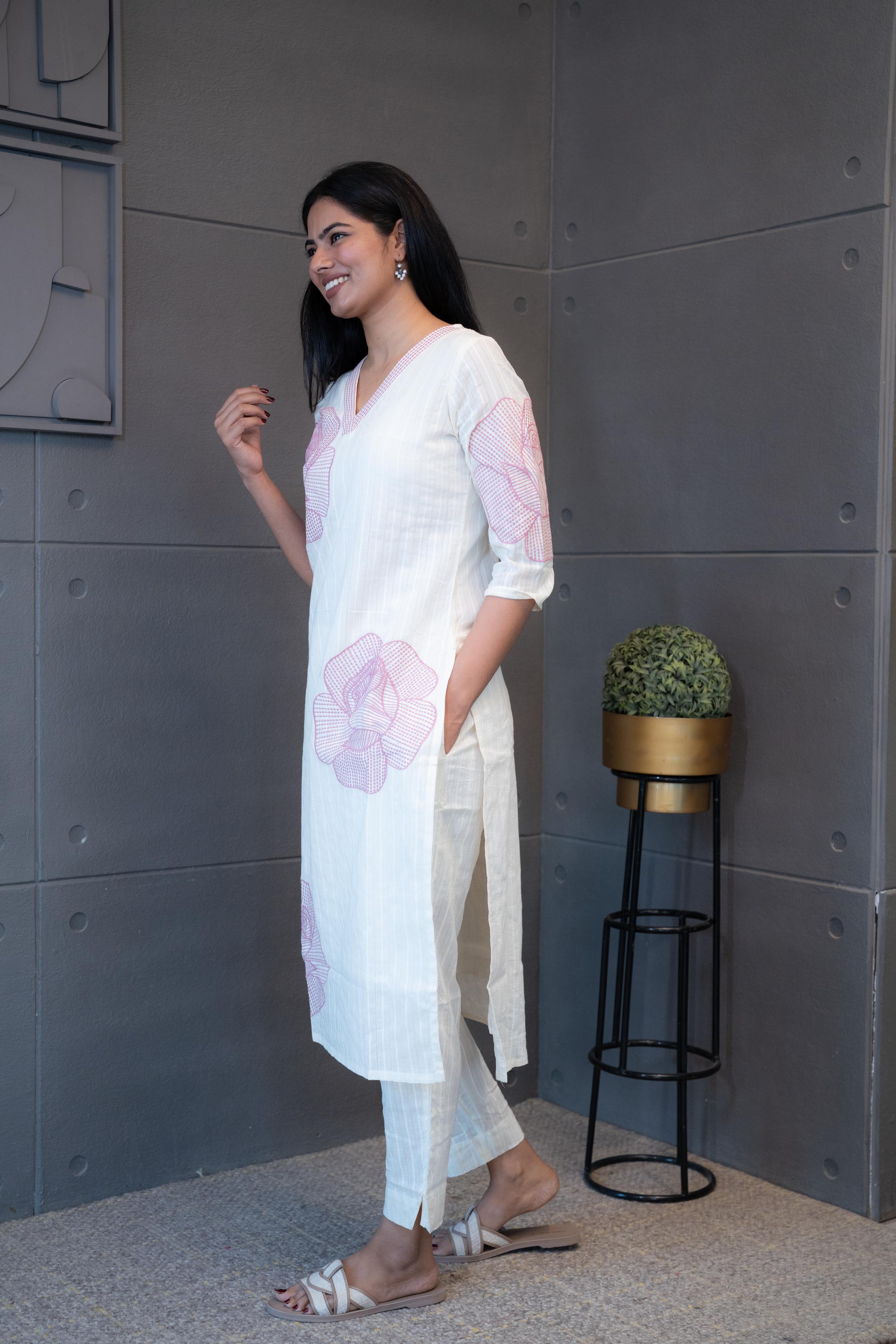 A woman modeling 'Pink Thread Kurta Set' by Tanauri, featuring a white cotton kurti and trousers with delicate pink floral embroidery