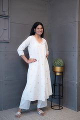 Close-up of the vibrant blue, pink, and yellow geometric triangle and circle embroidery on the cream cotton fabric of the Tanauri Kurta