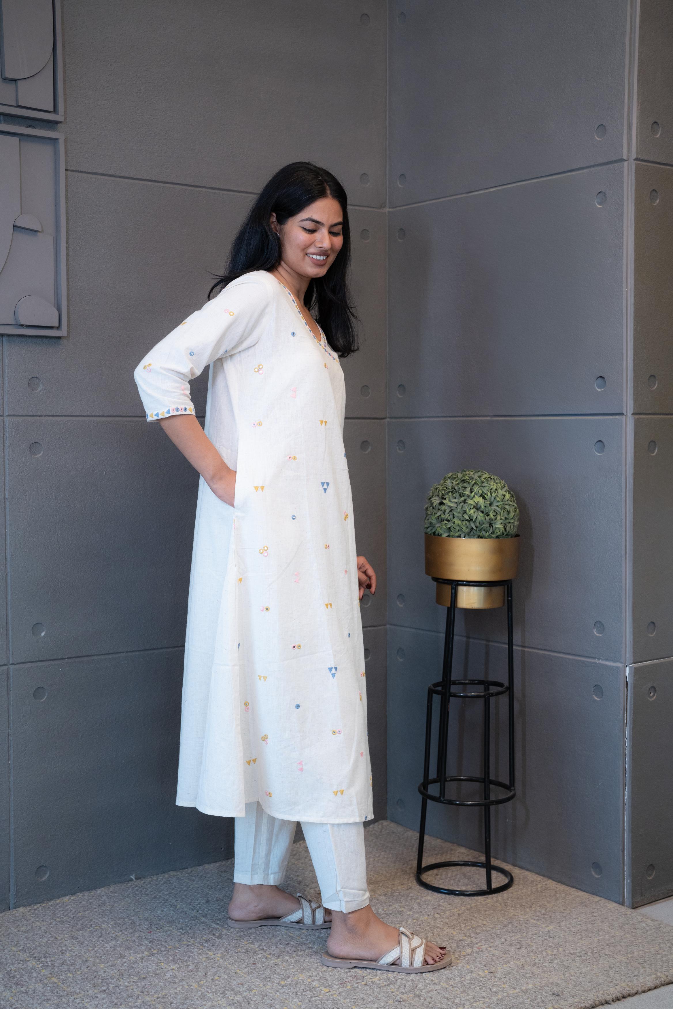 Tanauri Geometric Embroidered Cream Kurta Set, folded in packaging, showcasing colorful blue, pink, and yellow geometric embroidery on a light cotton kurti