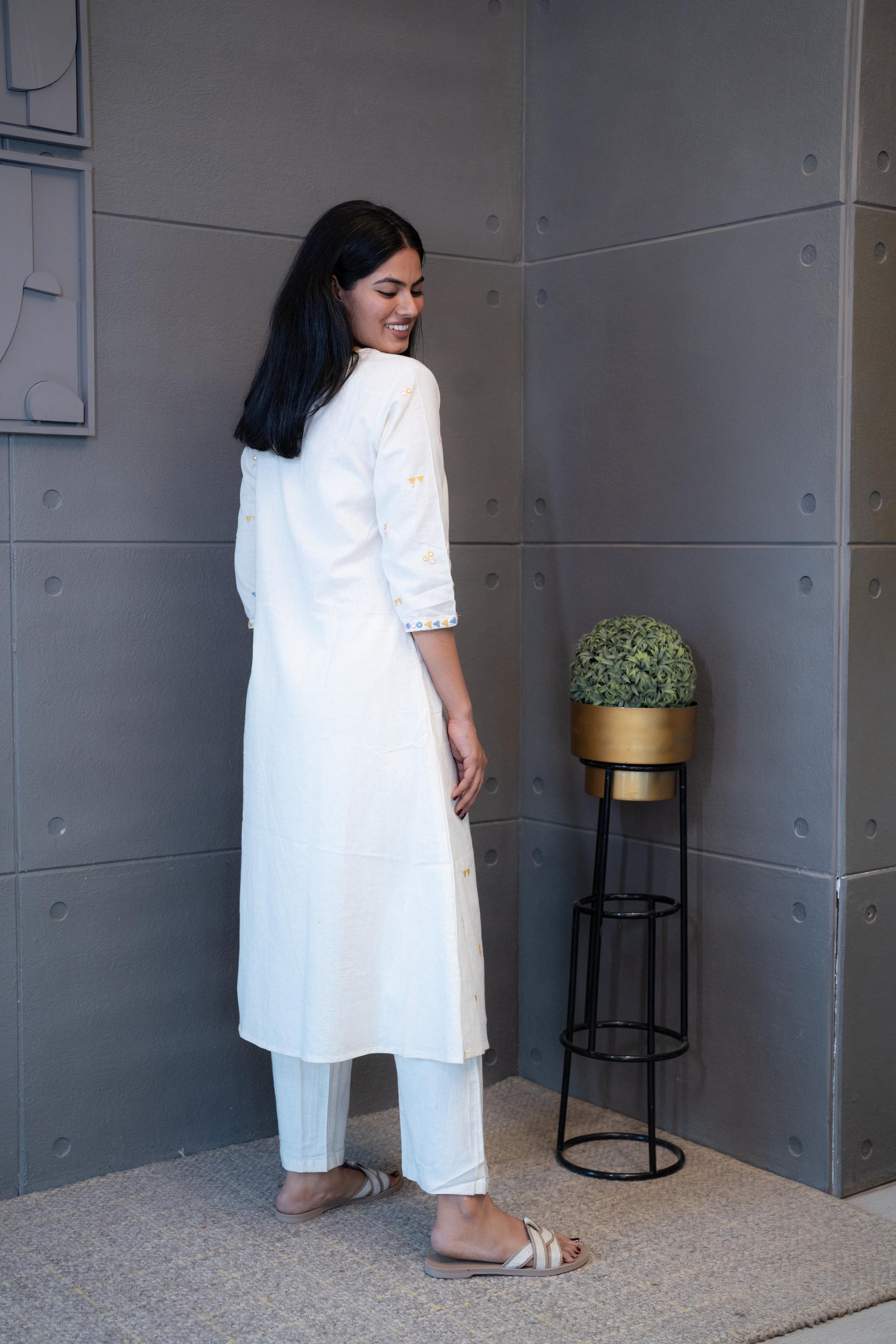 Model wearing Tanauri Geometric Embroidered Cream Kurta Set, displaying full view of kurti with geometric embroidery and matching cream pants in a casual setting