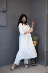 Tanauri Geometric Embroidered Cream Kurta Set, folded in packaging, showcasing colorful blue, pink, and yellow geometric embroidery on a light cotton kurti