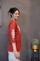 Close-up of the exquisite white floral rose and leaf embroidery on the terracotta fabric of the Tanauri Sun Baked Rose Short Kurti/Top, highlighting the intricate details