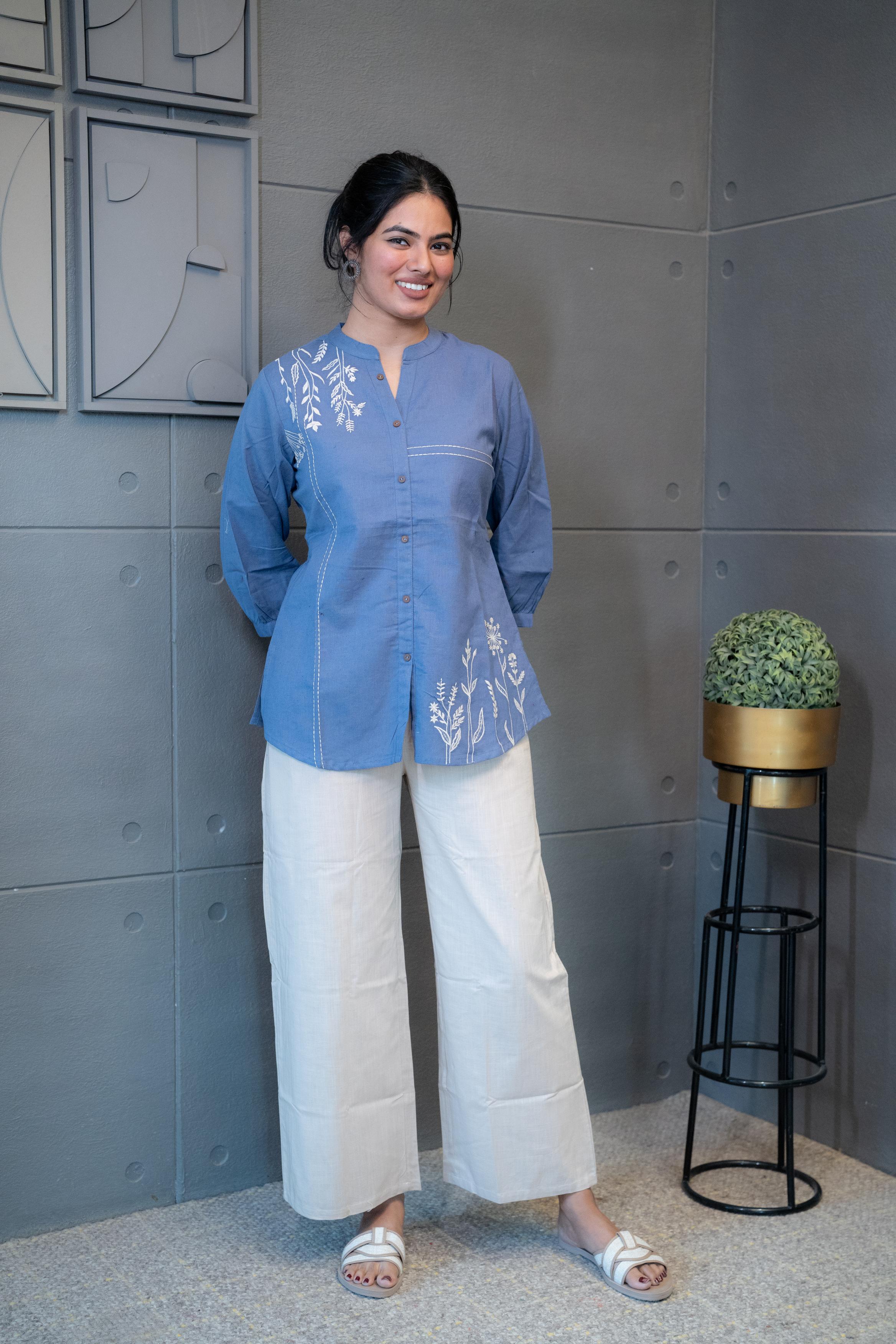 Tanauri Blue Pop Short Kurti/Top, folded in clear packaging, showcasing a blue cotton tunic with prominent white leafy embroidery on one side and a band collar with buttons