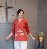 Tanauri Mastani Short Kurti/Top, folded in clear packaging, showcasing a vibrant brick red cotton tunic with prominent white vertical stripe detailing on the V-neckline