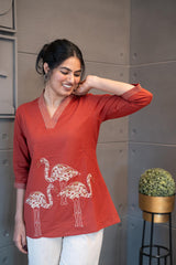 Tanauri Mastani Short Kurti/Top, folded in clear packaging, showcasing a vibrant brick red cotton tunic with prominent white vertical stripe detailing on the V-neckline