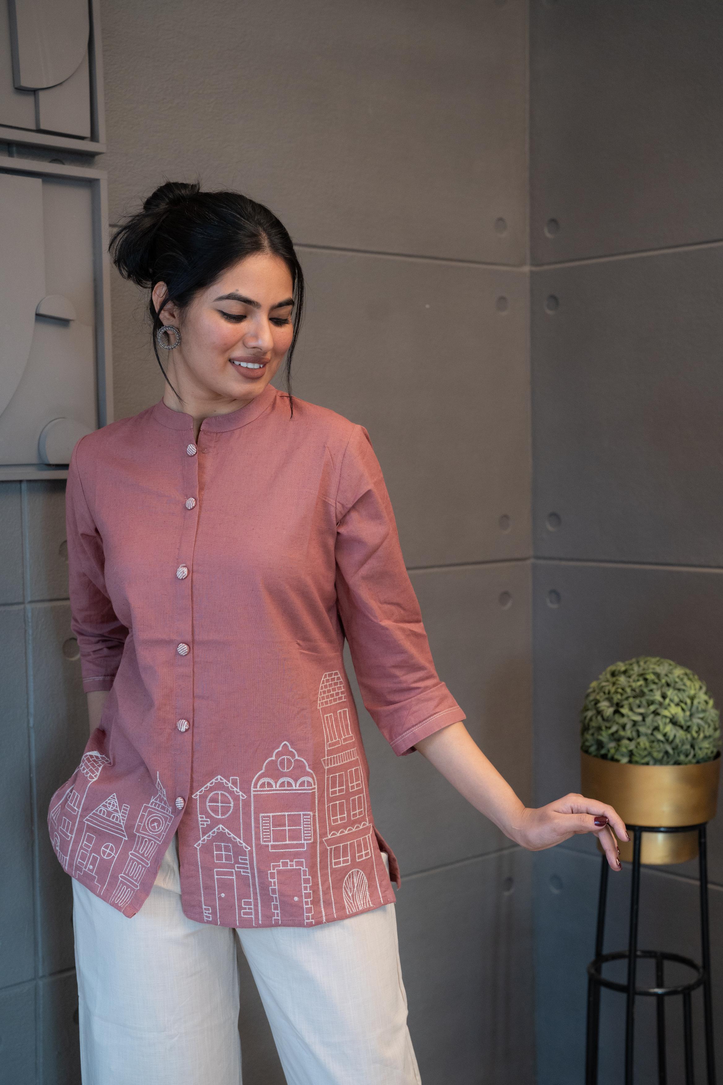 Tanauri Pink Cityscape Short Kurti/Top, folded in clear packaging, showcasing a plain blush pink cotton tunic with subtle button details on the front placket