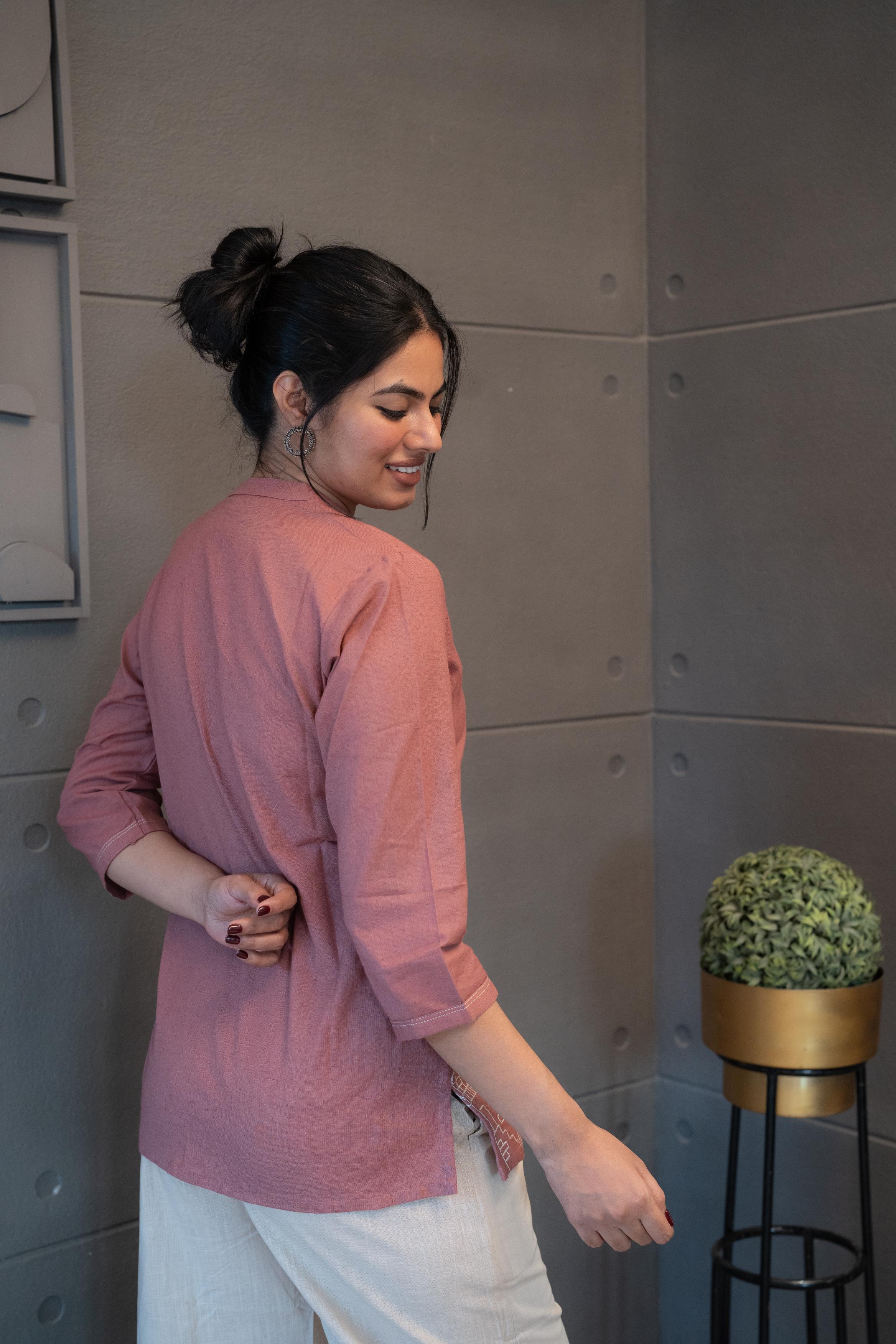 Tanauri Pink Cityscape Short Kurti/Top, folded in clear packaging, showcasing a plain blush pink cotton tunic with subtle button details on the front placket