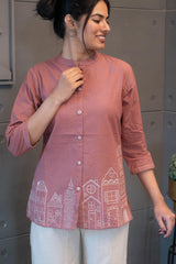 Model wearing Tanauri Pink Cityscape Short Kurti/Top, displaying the blush pink cotton short kurti paired with white pants for a fresh and casual everyday look