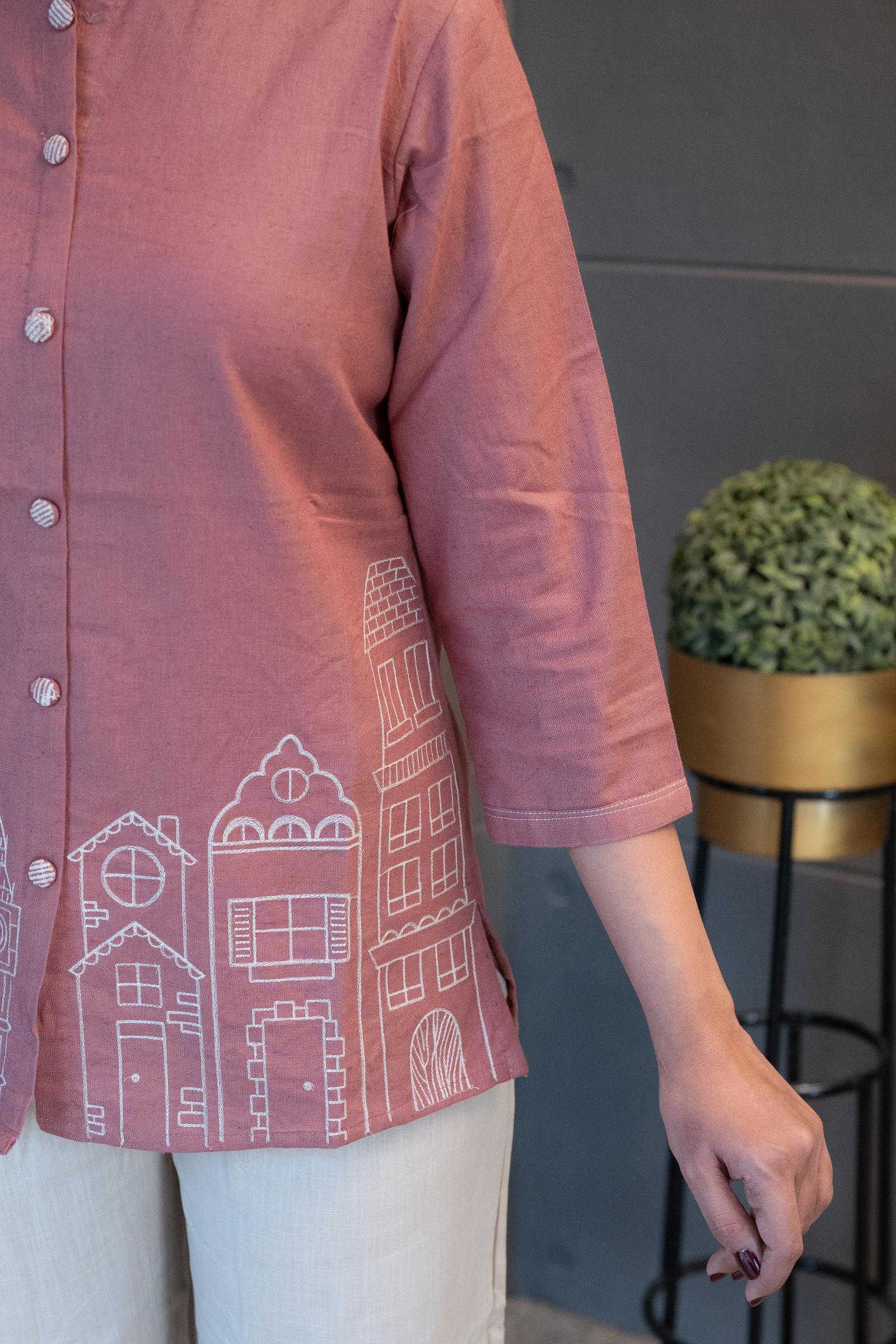 Close-up of the front placket and subtle button/decorative details on the blush pink fabric of the Tanauri Pink Cityscape Short Kurti/Top
