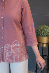 Close-up of the front placket and subtle button/decorative details on the blush pink fabric of the Tanauri Pink Cityscape Short Kurti/Top