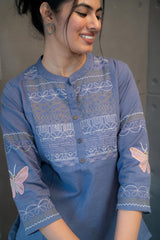 Close-up of the intricate white multi-patterned embroidery on the blue fabric of the Tanauri Orchid Short Kurti/Top, showing various swirls and geometric designs