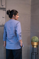 Tanauri Grey Bird Short Kurti/Top, folded in clear packaging, showcasing a periwinkle blue cotton tunic with light grey bird motifs and matching V-neck stitching