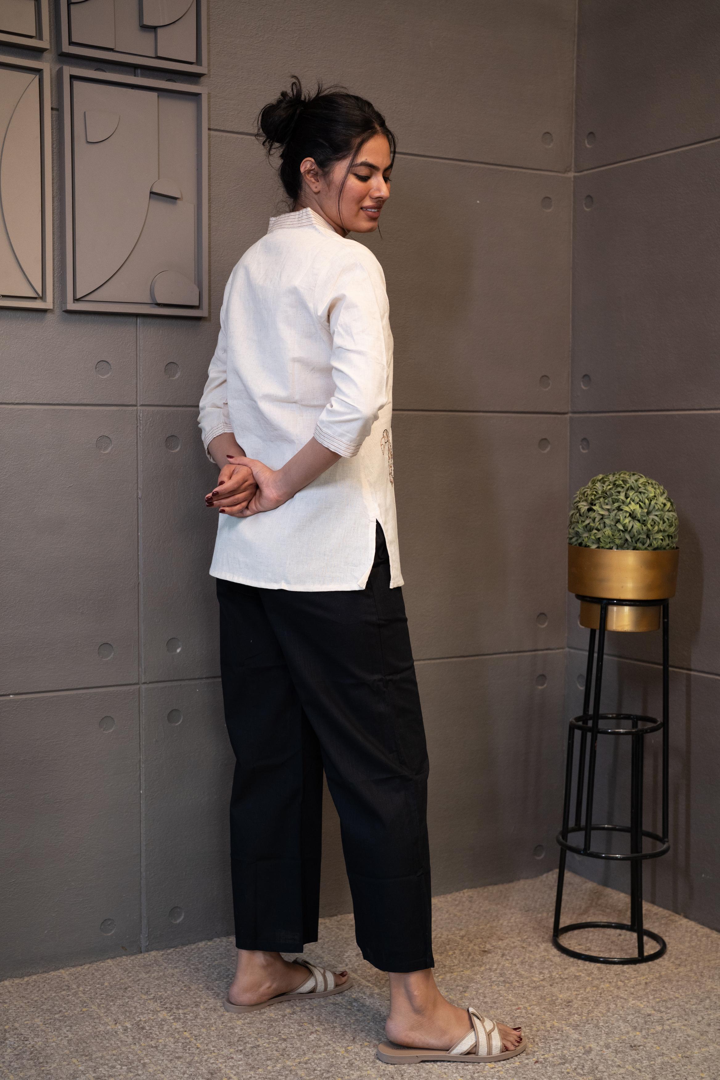 Tanauri Swan Short Kurti/Top, folded in clear packaging, showcasing an off-white/cream cotton tunic with subtle vertical detailing on the V-neckline