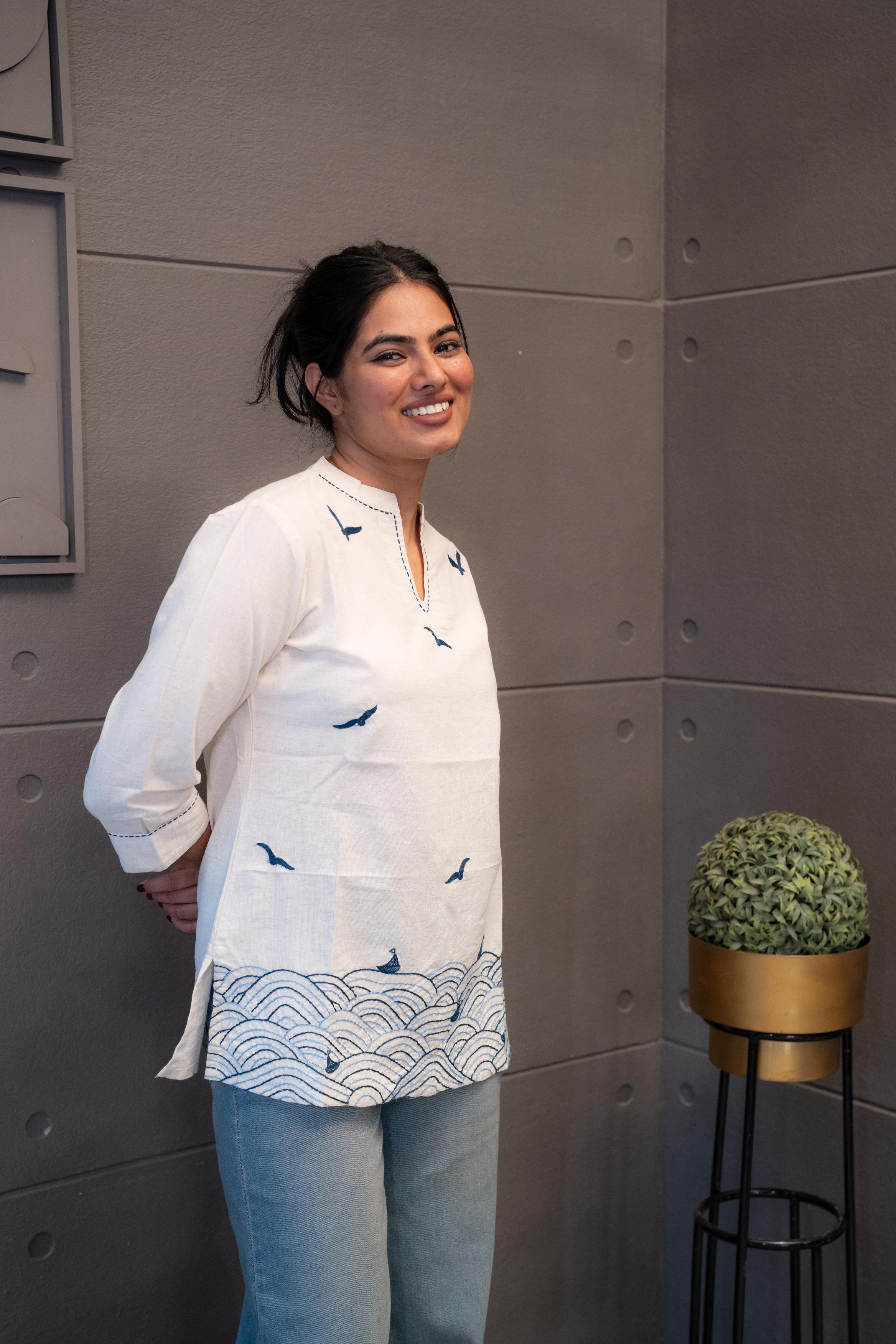 Model wearing Tanauri Blue Bird Short Kurti/Top, displaying the cream cotton short kurti with blue bird designs, paired with blue jeans for a charming casual look