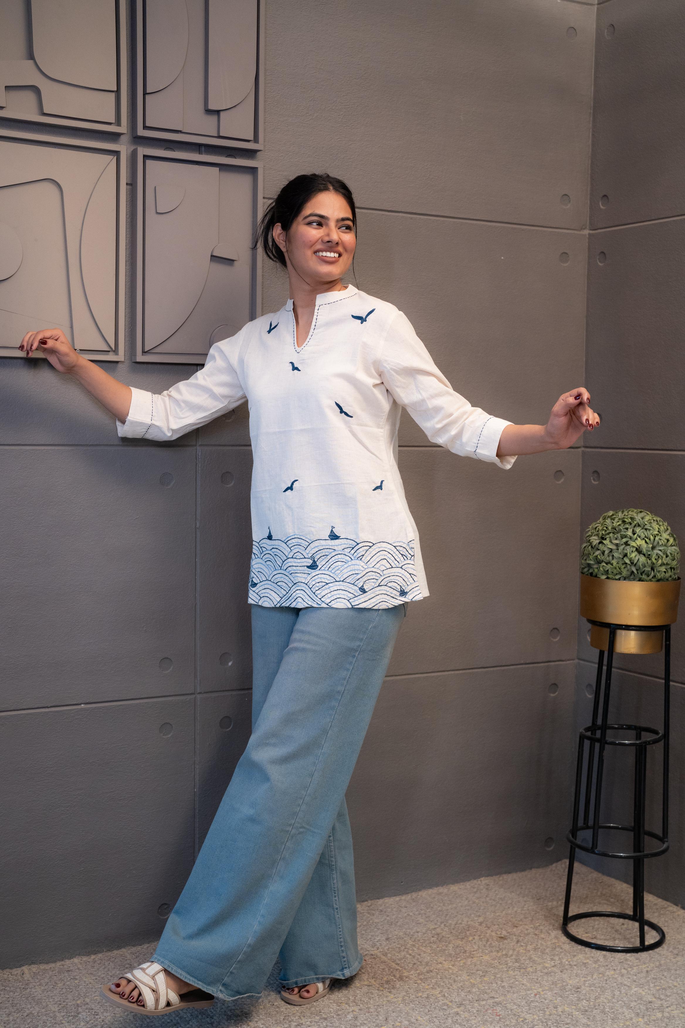 Model wearing Tanauri Blue Bird Short Kurti/Top, displaying the cream cotton short kurti with blue bird designs, paired with blue jeans for a charming casual look