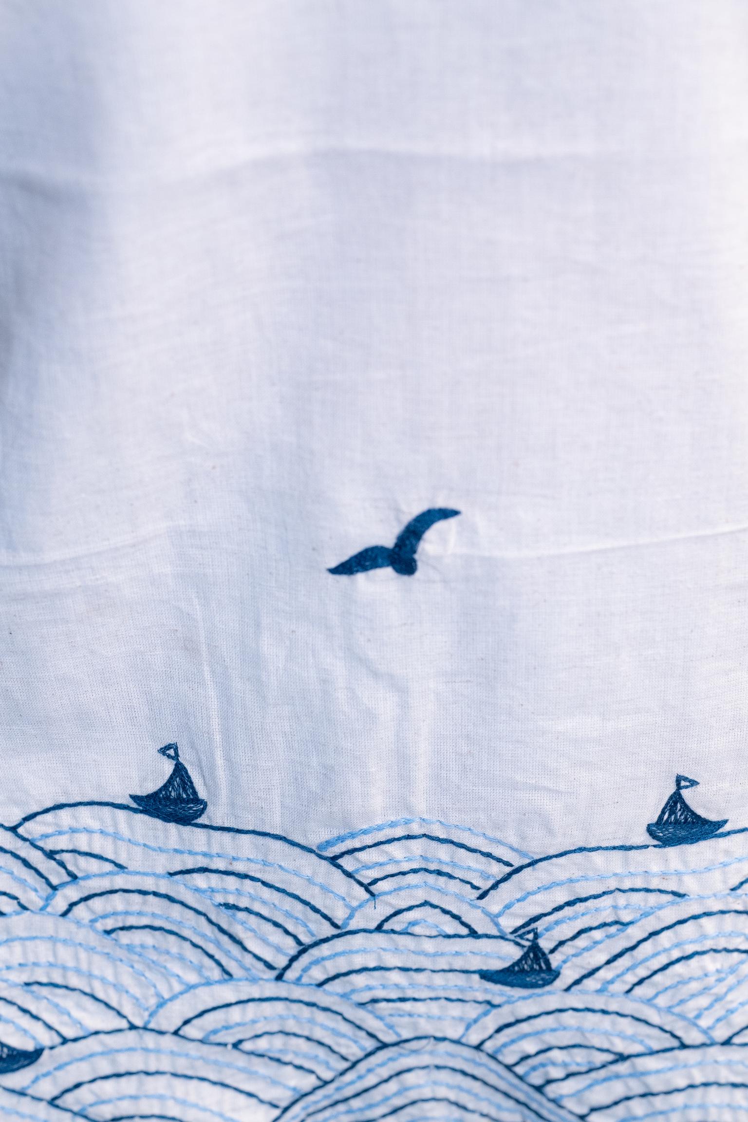 Tanauri Blue Bird Short Kurti/Top, folded in clear packaging, showcasing an off-white cotton tunic with blue bird motifs and blue V-neck stitching