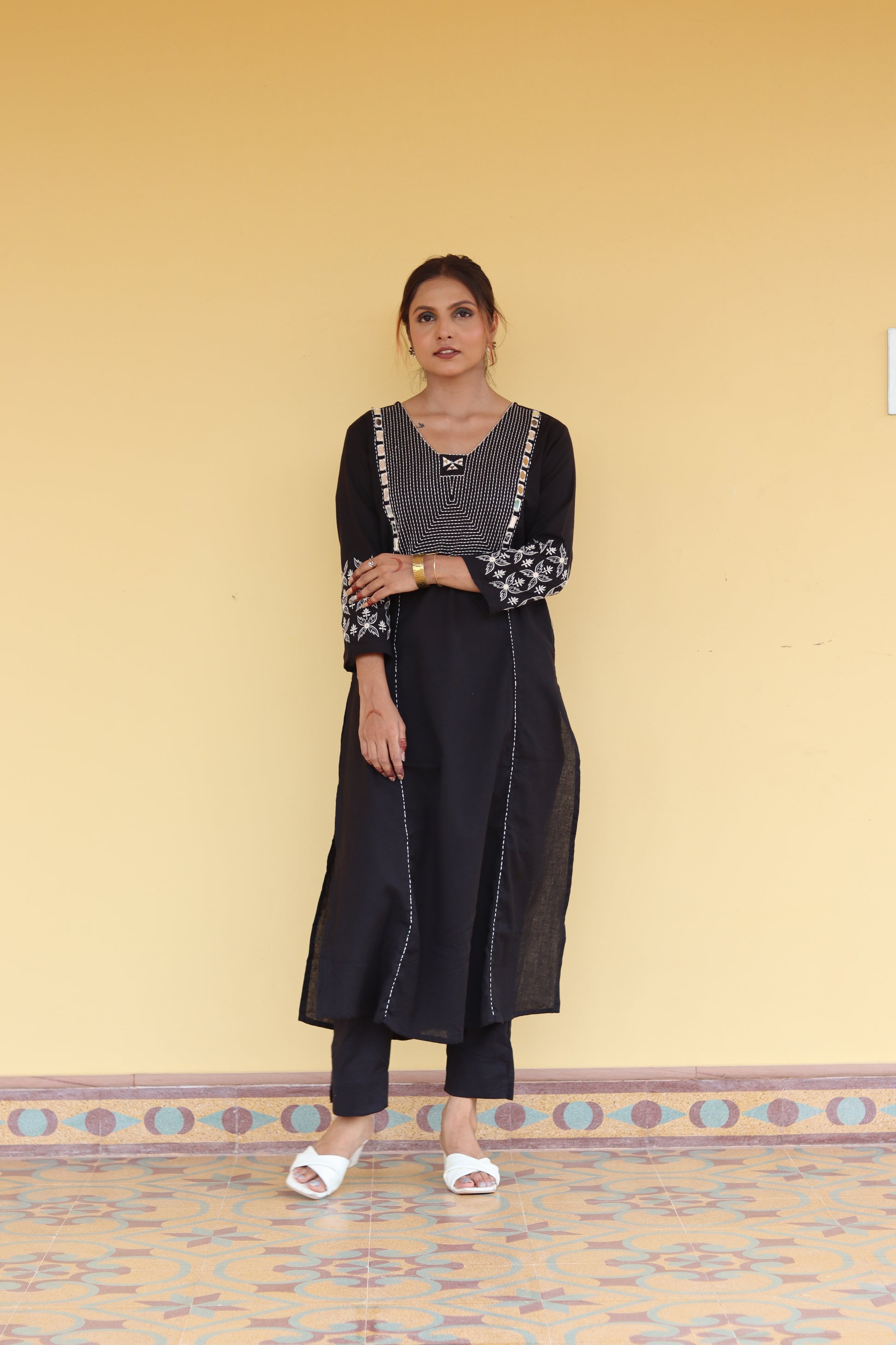 Woman in a black outfit with floral patterns standing on a patterned rug.
1. Black cotton kurti with round neck and three-quarter sleeves  
2. Elegant black straight-fit kurti with gold detailing  
3. Pure cotton black kurti – everyday ethnic wear  
4. Black kurti for women with minimal embroidery  
5. Stylish black kurti with side slit and button design  
6. Festive black kurti with mirror work and V-neck  
7. Classic black kurti with mandarin collar and front placket  
8. Casual wear black kurti in breath
