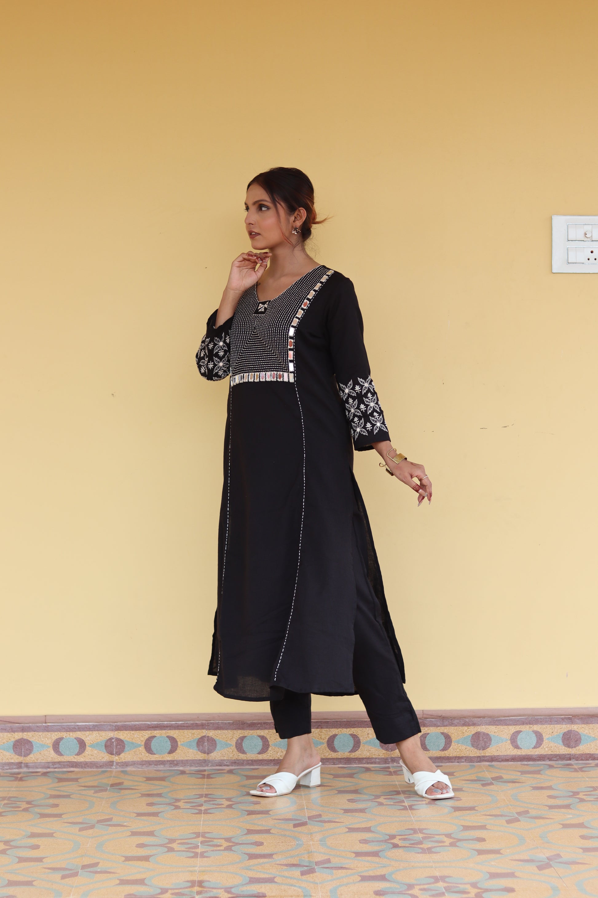 Woman in a black outfit standing on a patterned rug with a beige wall in the background.
1. Black cotton kurti with round neck and three-quarter sleeves  
2. Elegant black straight-fit kurti with gold detailing  
3. Pure cotton black kurti – everyday ethnic wear  
4. Black kurti for women with minimal embroidery  
5. Stylish black kurti with side slit and button design  
6. Festive black kurti with mirror work and V-neck  
7. Classic black kurti with mandarin collar and front placket  
8. Casual wear black 