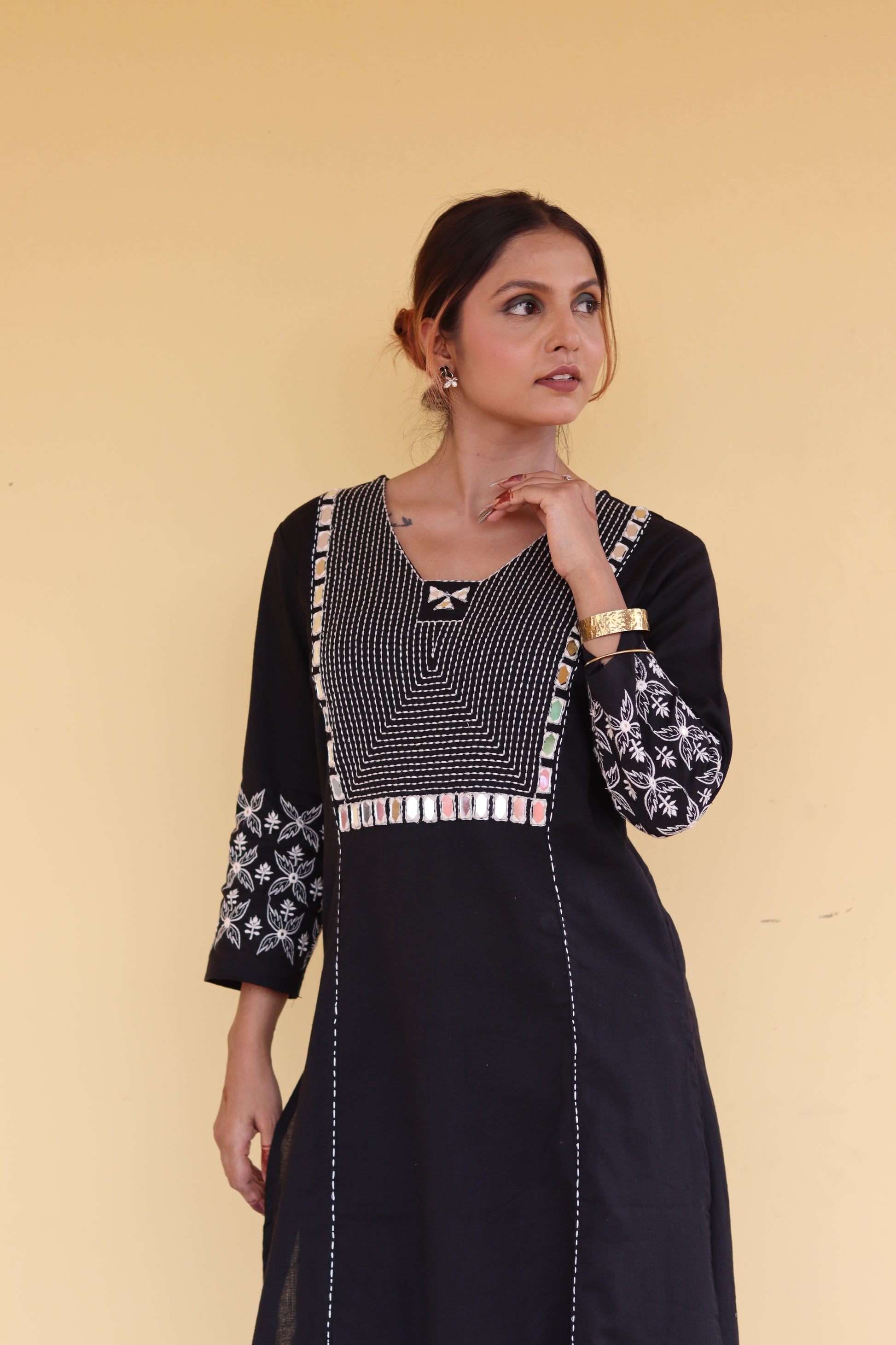 Woman wearing a black dress with geometric patterns on a beige background
1. Black cotton kurti with round neck and three-quarter sleeves  
2. Elegant black straight-fit kurti with gold detailing  
3. Pure cotton black kurti – everyday ethnic wear  
4. Black kurti for women with minimal embroidery  
5. Stylish black kurti with side slit and button design  
6. Festive black kurti with mirror work and V-neck  
7. Classic black kurti with mandarin collar and front placket  
8. Casual wear black kurti in breath