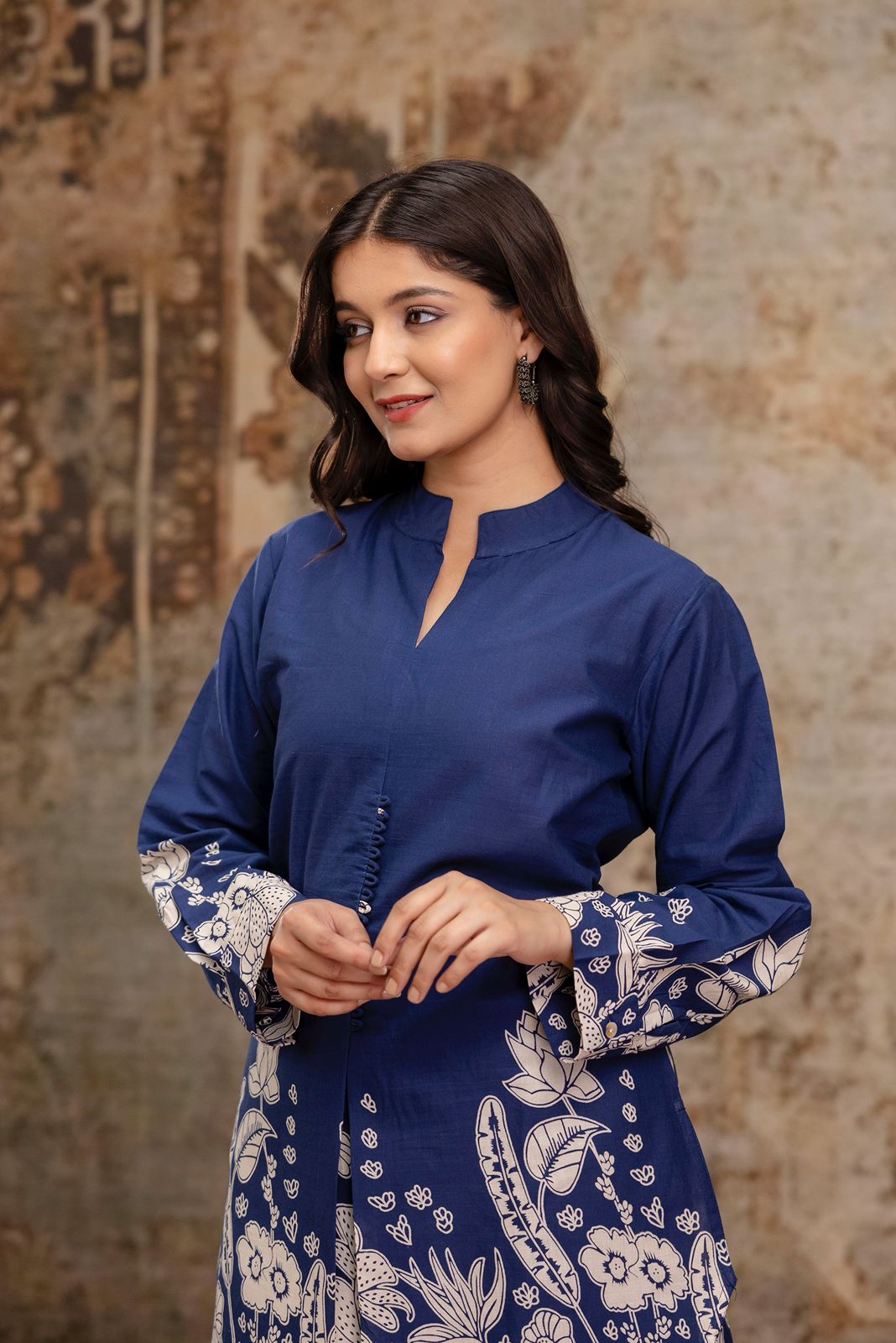1. Close-up of navy blue cotton kurti with white floral block printed cuffs  
2. Navy ethnic kurti for women with mandarin collar and handcrafted buttons  
3. Blue kurti with detailed floral prints and full sleeves – front close-up  
4. Model in navy cotton kurti with printed sleeves and minimal earrings  
5. Portrait of woman wearing navy kurti with ethnic floral motifs  
6. Front upper view of navy kurti featuring button placket and sleeve print  
7. Elegant navy ethnic kurti with floral print detailing 